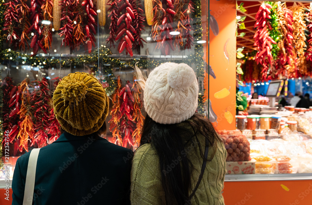 Fototapeta premium People looking at market display of red peppers and dried corn, exploring local food and culture