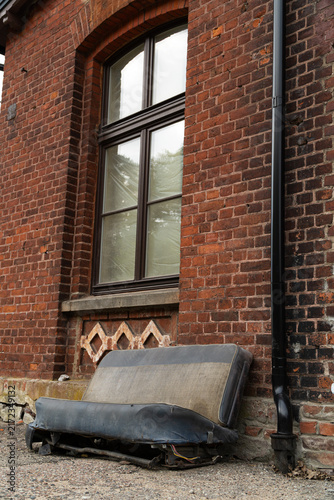 фотографія Old abandoned sofa seat discarded against a weathered red brick wall with vintag