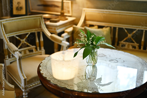 Elegant interior with a small bouquet of lily of the valley flowers displayed in a glass vase on a round table