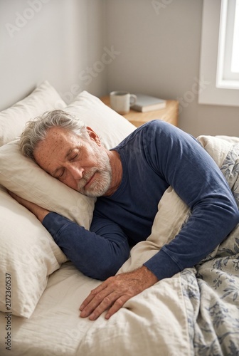 Older man sleeping peacefully curled on his side in bed