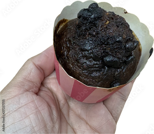 isolated person holding a homemade chocolate banana oat muffin with chocolate chips in a paper cup for a snack concept, white background 