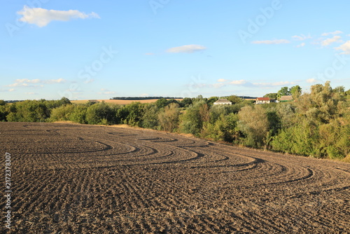 Curved circular plow patterns on rich black soil in an agricultural field after tractor cultivation