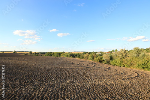 Curved circular plow patterns on rich black soil in an agricultural field after tractor cultivation