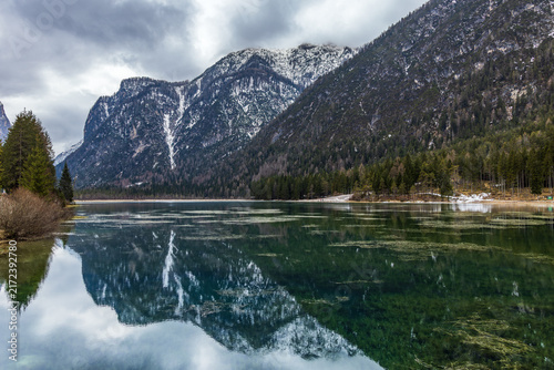 Canvas Print Lake Olanger Reservoir in South Tyrol Italien, Serene mountain lake reflects snowy peaks and evergreen trees