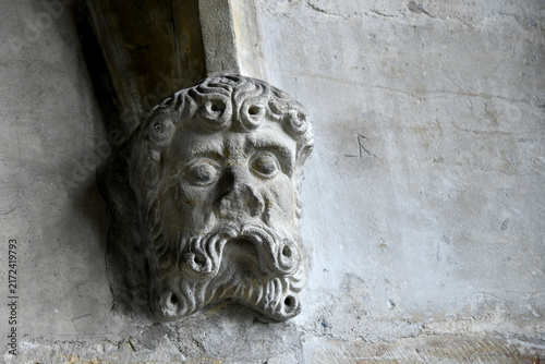 Cuadro en lienzo A close-up view of a carved stone wall corbel shaped as a bearded male face with stylized curly hair and mustache, supporting an arch inside Prague Castle