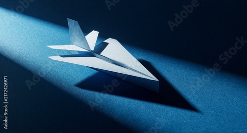 Paper Airplane on Blue Background with Dramatic Lighting and Shadows
