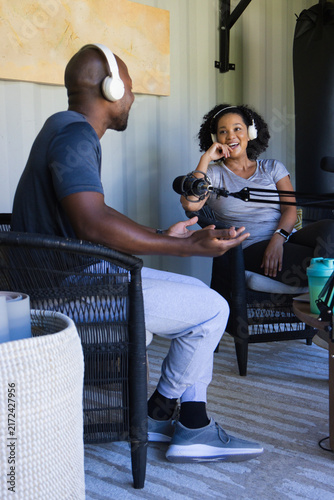 Diverse podcast hosts recording chat in metal studio wearing headphones and using microphone