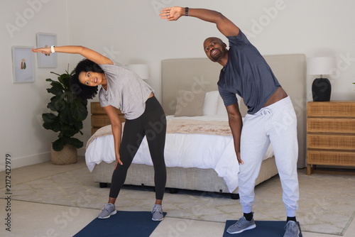 Bild auf Leinwand Diverse couple stretching laterally on dark blue mats in bedroom with bed and la