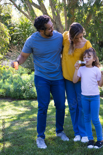 African American family on lawn, bottle and keys, dad in tee, child blowing bubbles with white-wand