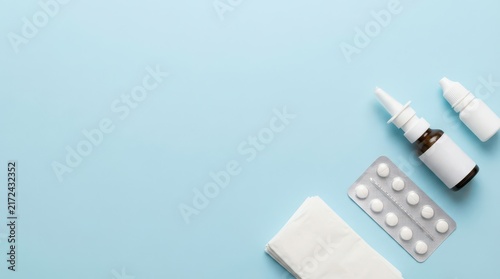 Top view allergy care composition with nasal spray blister tablets and tissues on pastel blue background for medical banner and background use. Copy space