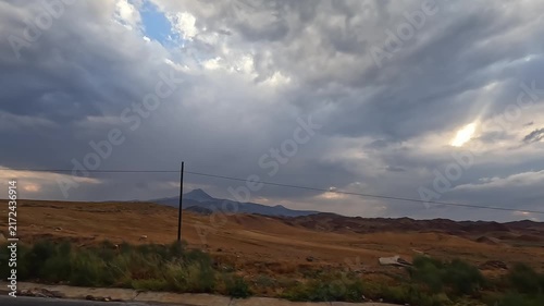 Turkish countryside unfolds in wide view under dramatic storm clouds, showing rural road travel for tourism promotion, destination marketing, transport planning, and changing weather context