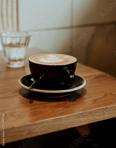 Cappuccino with Latte Art on Wooden Cafe Table