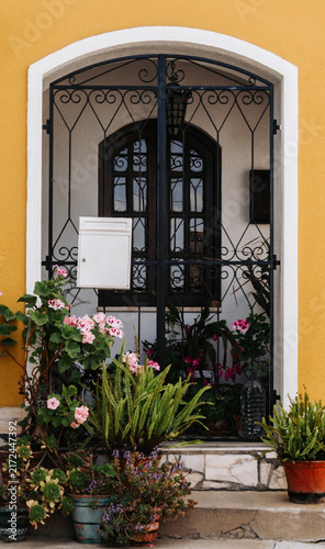 Traditional Mediterranean House Entrance with Flowers and Wrought Iron Gate