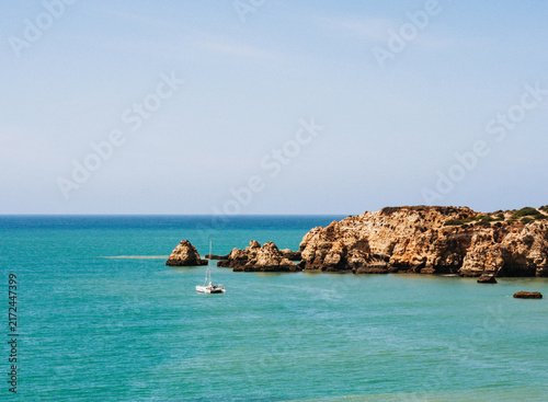 Sailboat Near Rocky Cliffs in Turquoise Sea