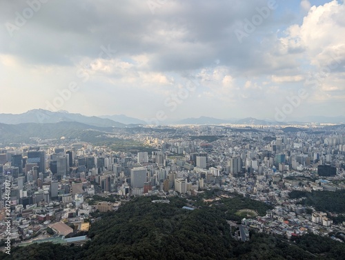 Canvas Print High altitude daytime view over the sprawling metropolitan city of Seoul, featuring dense architecture and distant mountain ranges