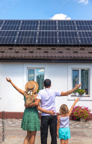 A family looks at solar panels on the roof of a house. Selective focus.