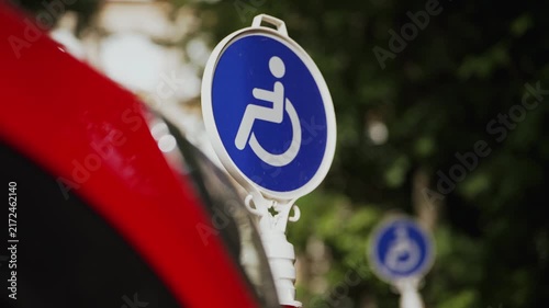 Reserved parking sign for people with disabilities in a public parking area. Accessibility symbol highlights inclusive mobility, equal access, and wheelchair-friendly infrastructure.