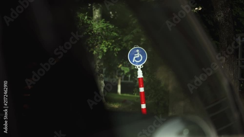 Accessible parking sign viewed through a car window at night, marking a reserved space for people with disabilities. Accessibility, inclusion, equal access, mobility rights, and urban infrastructure.