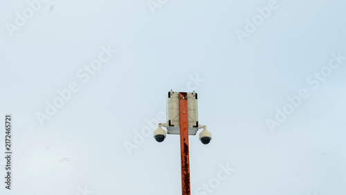 Принти на полотні In the bright and expansive sky, a set of surveillance cameras is mounted atop a sturdy post