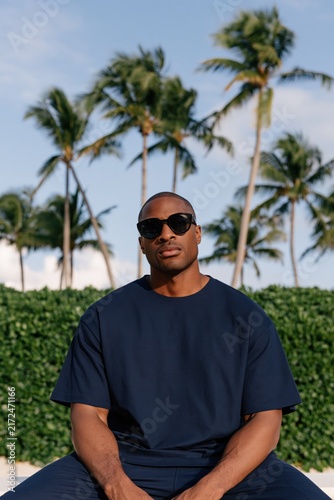 Stylish male portrait with sunglasses and palm trees for tropical portrait background and fashion banner design
