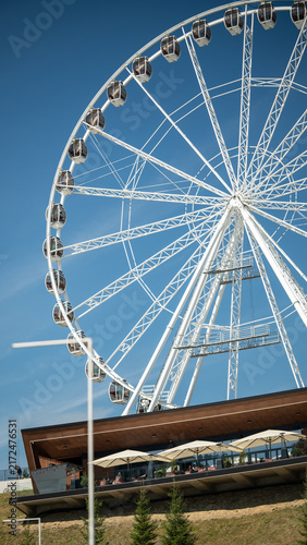 Ferris wheel stands tall against clear sky near outdoor seating area