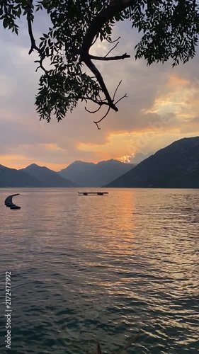Timelapse of sunset over calm Bay of Kotor framed by mountains as the sun slowly dips below the peaks. Perast, Montenegro