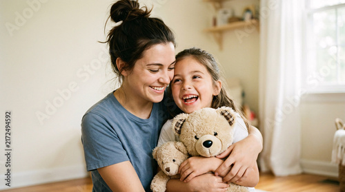 Mother and daughter laughing while holding teddy bears indoors