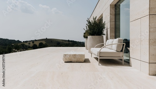 Minimal luxury terrace with outdoor sofa and stone coffee table beside modern residence | Contemporary outdoor living space overlooking rolling countryside