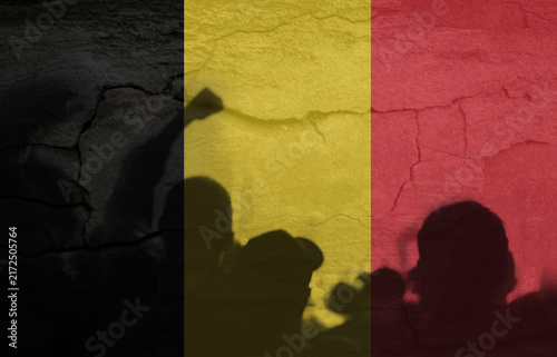 Obraz na płótnie Silhouettes of protesting people casting shadows against a cracked wall with the Belgian flag texture