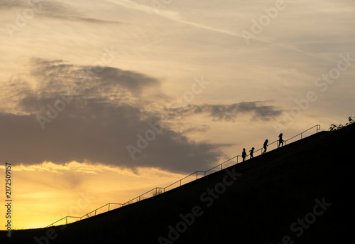 Four people climbing the stairs up Monks Mound at sunset.
