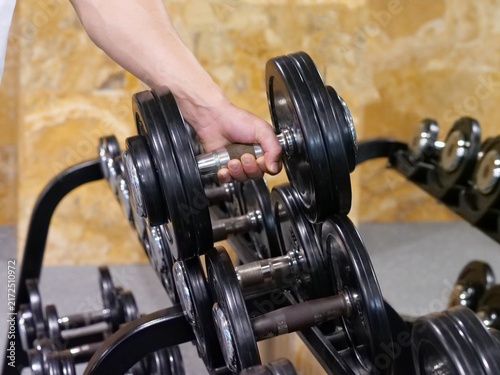 Fotografía Close-Up View of Athlete Hand Gripping Heavy Steel Dumbbell on Gym Storage Rack