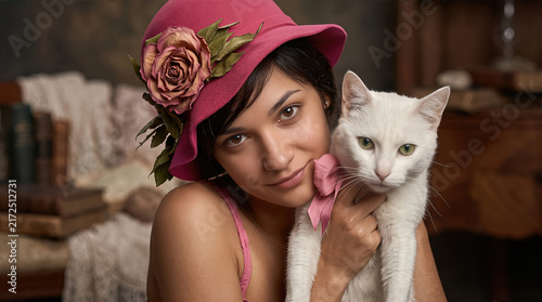 Vintage portrait of a woman wearing a 1920s cloche hat holding a domestic cat Felis catus