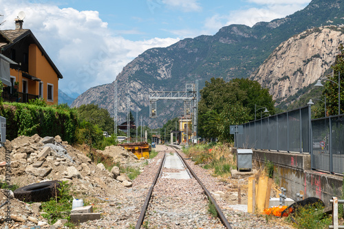 Railroad tracks, tunnel entrance, train, nature, mountain landscape, vegetation, metal structures, pylons, stone, railway construction site, transportation, summer, day, perspective, path, track