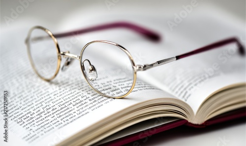 Naklejka Open book with eyeglasses resting on the pages 
