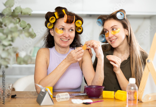 Canvastavla Adult and young women curl their hair with curlers and use hydrogel eye patches