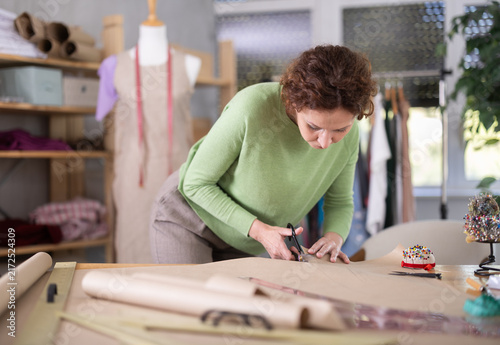 Konstfotografi Female tailor cutting paper with scissors, cutting out the outline of a pattern