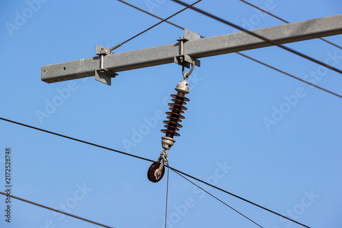 Overhead line insulator and tension pulley against blue sky