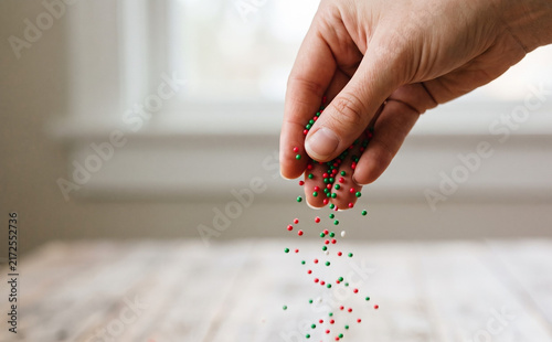 Close up of a woman hand scattering colorful sweet sprinkles for baking and holiday desserts