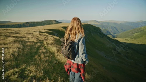 Hiking on a mountain path during a sunny day in the countryside with a person carrying a backpack