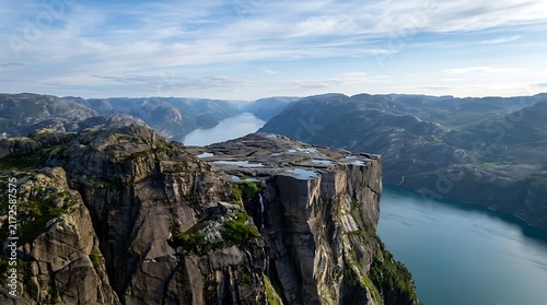 High cliff overlooking deep blue fjord and majestic mountain range
