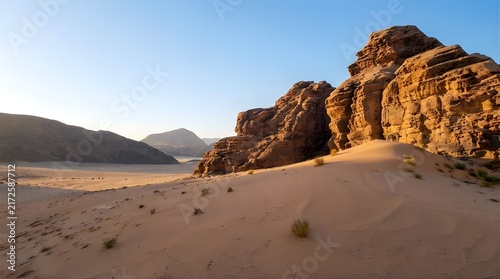 Arid desert landscape with sand and weathered rock formations

