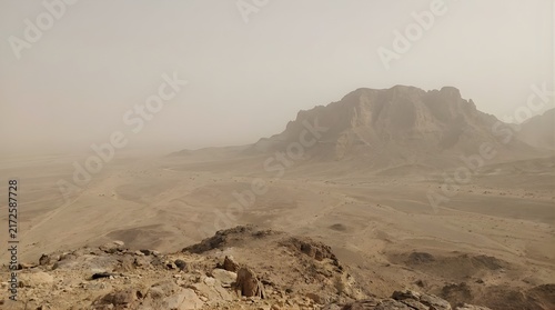 Hazy desert landscape with dusty mountains and sandy ground
