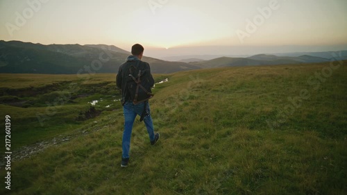 Walking on a grassy hill during sunset in the mountains
