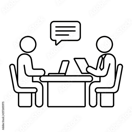 Two people in a business meeting, sitting at a desk with a laptop and documents, discussing work