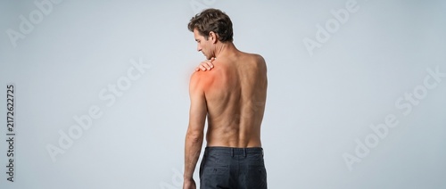 Man Experiencing Shoulder Pain Against a Neutral Background