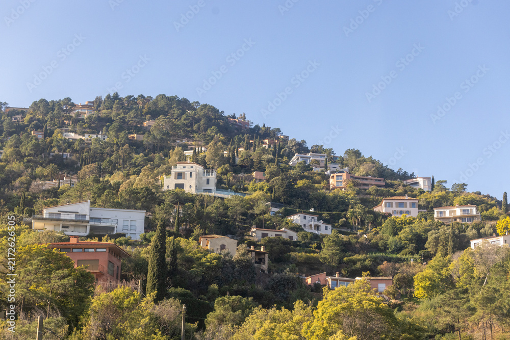 Naklejka premium Provence, France , December 31, 2025: Upscale Mediterranean villas cling to steep volcanic rocks of the Esterel Massif between Cannes and Nice.