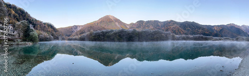 Photography Morning mist lingers over the perfect reflection of Mount Yake on Taisho Pond's mirror-like water