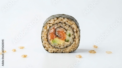 Single Sushi Roll Piece Standing Upright Spiral Cross Section Rice Grains Scattered Pure White Background

