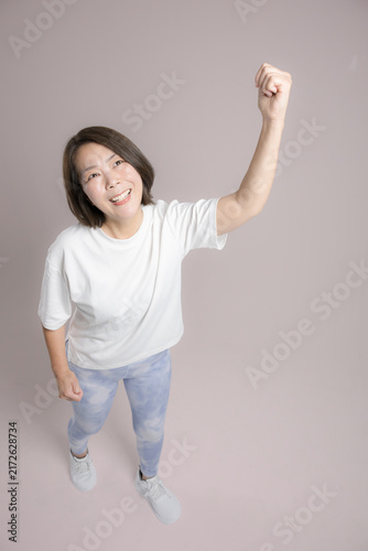 Fotografía [Pink Background] A woman exercising with a smile and her arms raised high in a