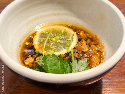 Fototapeta つけ麺のスープ。魚介出汁ベースにみつばとあげ玉とレモンをトッピングした醤油味のおつゆ。